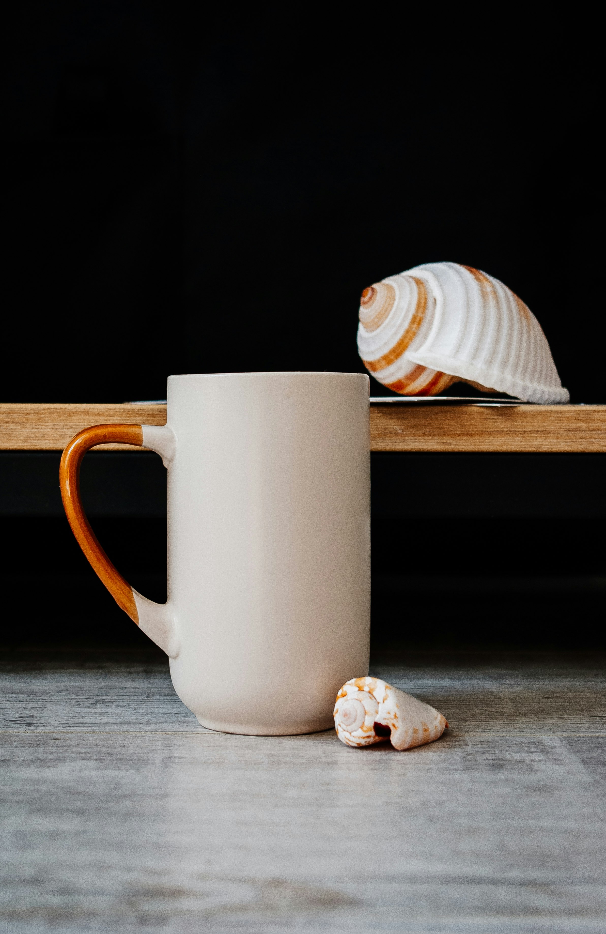 white and brown striped ceramic mug on brown wooden table